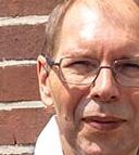 Der erfolgreiche Umschüler André Pardun steht mit verschränkten Armen vor einer geziegelten Hauswand.