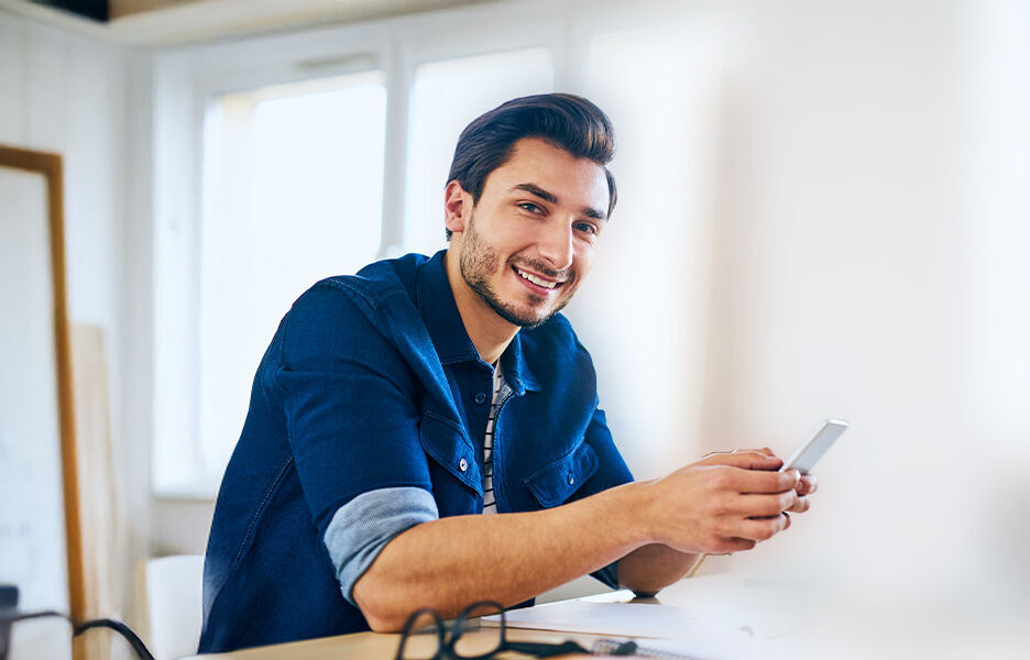 ein Mann, der an einem Schreibtisch sitzt und eine Zelle benutzt