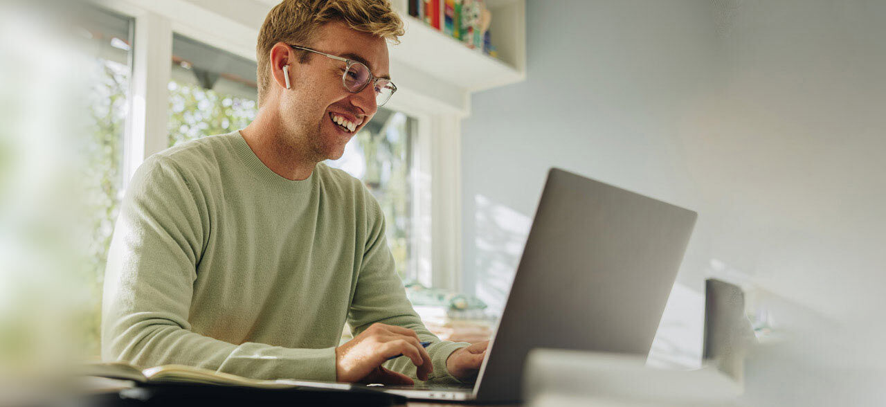 ein Mann sitzt an einem Tisch mit einem Laptop in einem Klassenraum